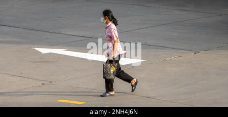SAMUT PRAKAN, THAILANDIA, 30 2023 GENNAIO, Una donna con una maschera sul suo viso sta correndo su una strada Foto Stock