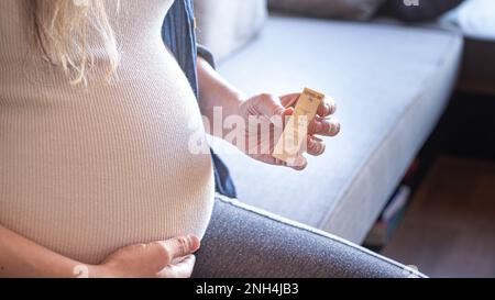 Donna in gravidanza con risultati positivi utilizzando un dispositivo di test rapido per COVID-19 Foto Stock