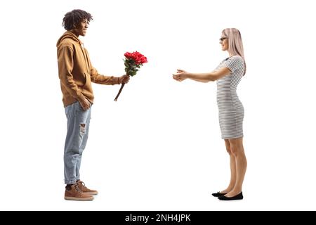 Giovane afro-americano che dona rose rosse ad una donna caucasica sorpresa isolata su sfondo bianco Foto Stock