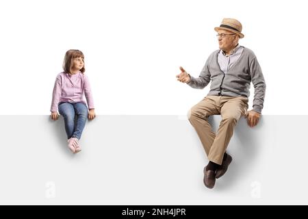 Nonno che parla con una bambina seduta su un pannello vuoto isolato su sfondo bianco Foto Stock