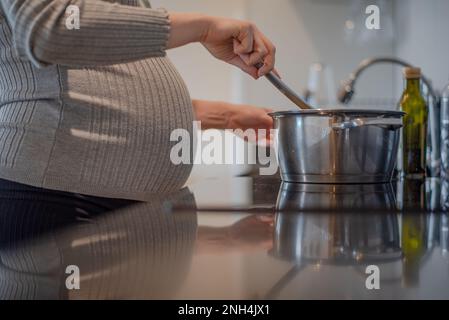 donna incinta che prepara pasti postpartum Foto Stock