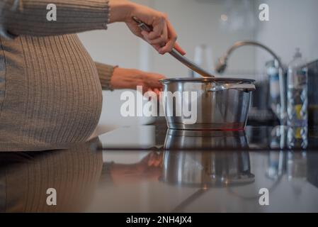 donna incinta che prepara pasti postpartum Foto Stock