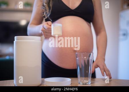 Donna incinta che tiene una paletta con siero di latte Foto Stock