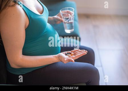 Donna incinta che assume capsule di integratore nutrizionale Foto Stock