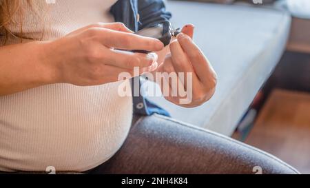 Primo piano della donna incinta che sta monitorando il suo glucosio nel sangue Foto Stock