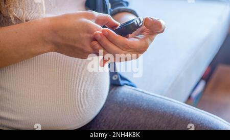 Primo piano della donna incinta che sta monitorando il suo glucosio nel sangue Foto Stock