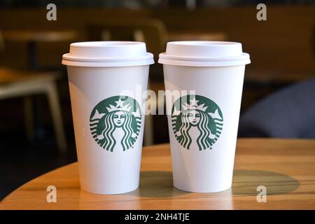 Austin, Texas - Febbraio 2023: Due tazzine di carta con il logo Starbucks su un tavolo in una delle catene di caffetterie dell'azienda Foto Stock