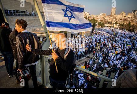 Gerusalemme, Israele. 20th Feb, 2023. Un uomo prende s selfie mentre i manifestanti marciano mentre sventolano bandiere israeliane durante una dimostrazione. Manifestazioni di massa contro la riforma giudiziaria si sono svolte a Gerusalemme e a Tel Aviv, mentre i legislatori israeliani sono stati chiamati a votare in prima lettura sulla riforma giudiziaria discussa in seno alla Knesset (parlamento israeliano). Credit: SOPA Images Limited/Alamy Live News Foto Stock