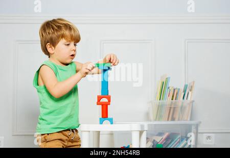 Giovane ragazzo edificio torre tra libri e giocattoli Foto Stock