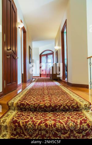 Lungo corridoio vuoto moquette / corridoio all'interno di un hotel moderno  fiancheggiato da porte in legno Foto stock - Alamy