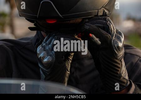 Primo piano dettaglio delle mani di un ciclista con guanti che indossa il casco. Concetto di sicurezza stradale Foto Stock