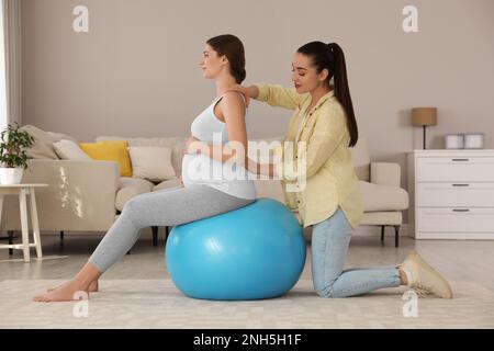 Doula lavora con una donna incinta in soggiorno. Preparazione alla nascita del bambino Foto Stock