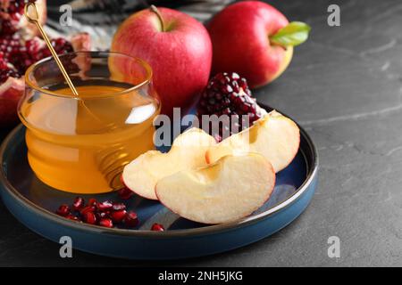 Miele, melograno e mele su tavola nera, primo piano. Rosh Hashana vacanza Foto Stock