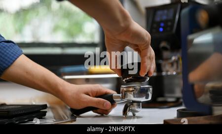 Barista professionista maschio che utilizza Macaron antimanomissione o caffè per distribuire il caffè prima di manomettere, preparando l'ordine del cliente nel bar Foto Stock