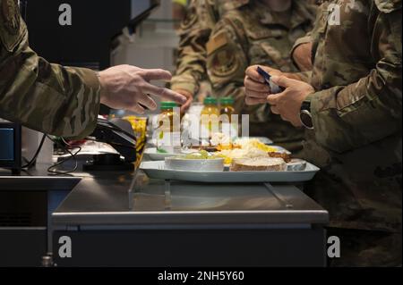 I militari della base aerea di Ramstein, Germania, si sono allerati per il cibo presso il Rheinland Inn Dining Facility durante la sua grande riapertura, il 18 luglio 2022. Il 786th Force Support Squadron includeva nuove stazioni alimentari come un panino e panini bar nel DFAC aggiornato. Foto Stock