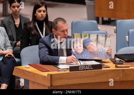 Durante la riunione del Consiglio di sicurezza, l'ambasciatore Gilad Erdan parla della situazione in Medio Oriente, compresa la questione palestinese presso la sede dell'ONU. Il Consiglio di sicurezza ha adottato all'unanimità la dichiarazione del Presidente del Consiglio di sicurezza proposta dagli Emirati Arabi Uniti che condanna l'espansione degli insediamenti israeliani nei territori palestinesi occupati. L'ambasciatore israeliano ha condannato gli attacchi terroristici contro i civili israeliani da parte dei militanti palestinesi e ha in mano una foto di due giovani fratelli Yaakov Paley, 6 anni, e Asher Paley, 8 anni, uccisi dal militante facendo sbattere un'auto in una fermata dell'autobus a Gerusalemme. Foto Stock