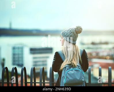 Solo in città. Ripresa di una giovane donna che guarda la vista della città da un ponte. Foto Stock