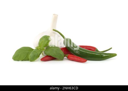 Peperoncini, rametto di basilico e bulbo d'aglio isolati su fondo bianco. Spezie e tema aromatizzante ancora vita Foto Stock