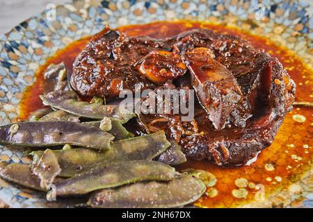 Agnello confit con piselli di neve in salsa sul piatto Foto Stock