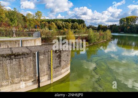 Un righello che indica il livello dell'acqua in uno stagno. Paesaggio autunnale sotto un cielo blu con nuvole chiare. Foto Stock