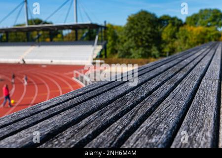 Vista ravvicinata della struttura di una panca in legno. Stadio sportivo fuori fuoco sullo sfondo. Foto Stock