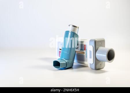 Dispositivi medici per malattie polmonari come asma, allergia e BPCO, misuratore di flusso di picco e spray blu pompa inalatore su sfondo grigio chiaro, spazio copia, s Foto Stock
