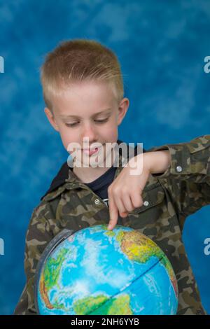 Piccolo ragazzo che mostra un globo terrestre contemporaneo della Terra Foto Stock