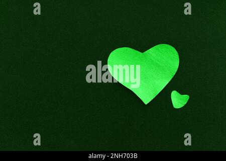 Cuore verde su sfondo verde scuro, fatto di carta, romantico e festivo bel simbolo, sfondo Foto Stock