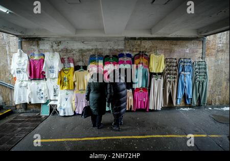 Kiew, Ucraina. 21st Feb, 2023. Un venditore e un cliente parlano sotto un sottopassaggio stradale il giorno della vendita. Il 24 febbraio 2023 segna il primo anniversario della guerra di aggressione russa contro l'Ucraina. Credit: Kay Nietfeld/dpa/Alamy Live News Foto Stock