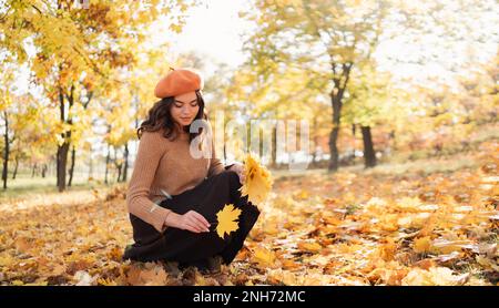 Felice giovane donna sorridente nel parco il giorno di autunno soleggiato raccogliere foglie di acero. Spazio di copia Foto Stock