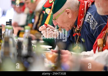 Riedlingen, Germania. 21st Feb, 2023. Kretschmann, primo ministro di Baden-Württemberg (centro, i Verdi/Bündnis 90, M), mangia un piatto di rana trippa al Municipio il martedì Shrove. Più di 300 stolti della gilda Gole 1865 partecipano al fumo di sigaro, al pasto di Froschkuttel del 192nd e alla successiva uscita dal municipio, e in seguito intendono giocare attraverso la città. La rana trippa è una specialità di Riedlingen. Si affettava lo stomaco di manzo sott'aceto. Credit: Felix Kästle/dpa/Alamy Live News Foto Stock