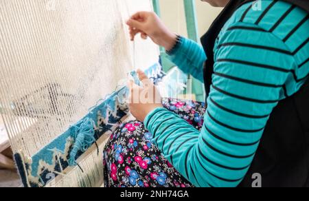 Giovane donna turca che lavora su un Loom tappeto Foto Stock