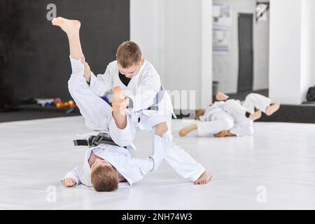 Ragazzi, bambini in kimono bianco, praticando il judo, esercizi jiu-jitsu al chiuso Foto Stock