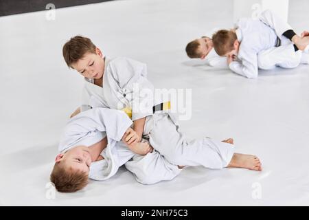 Ragazzi, bambini in kimono bianco, praticando il judo, esercizi jiu-jitsu al chiuso. Concorrenza. Forza Foto Stock