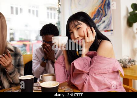 Multirazziale giovani felici che mangiano la pizza in pizzeria, bianco e nero allegri compagni ridere gustando il pasto divertirsi seduti insieme Foto Stock