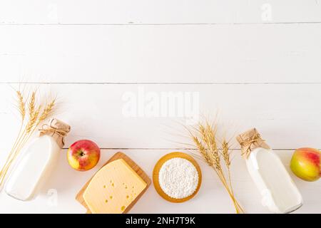 Un bellissimo sfondo festivo con una copia dello spazio della festa primaverile degli ebrei di Shavuot. latticini, orecchie, mele. vista dall'alto. bordo Foto Stock