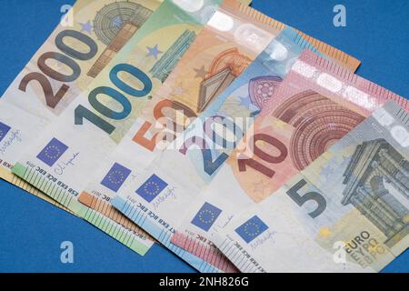 Diverse banconote in euro in fila primo piano, sfondo blu per i temi di finanza aziendale. Concetto di denaro mondiale, concetto di inflazione ed economia. Valuta Foto Stock