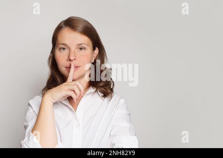 Ritratto della donna con il dito vicino alle labbra, segreto, silenzio e pettegolezzo concetto Foto Stock