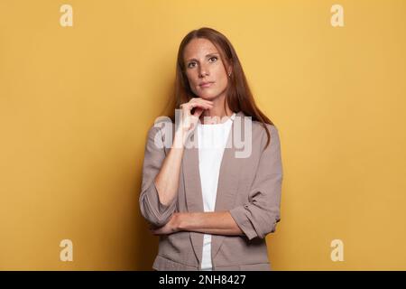 Donna d'affari media adulta in piedi contro sfondo giallo banner Foto Stock