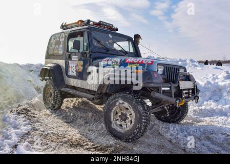 Un vecchio SUV Jeep Wrangler guida veloce nella neve su un angolo in una gara in Russia in Siberia. Foto Stock