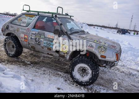 La vecchia macchina da fuoristrada 'Subaru 4x4' convertita da una berlina rapidamente con uno spruzzo di tempeste di neve va su una strada innevata in inverno al momento di girare la ruota Foto Stock