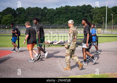 Gli studenti delle scuole superiori locali trasportano un altro studente durante una parte della sfida "questa è la mia squadra" come parte del campo estivo inaugurale di Fort Eustis al Todd Stadium, Newport News, Virginia, 21 luglio 2022. Il campo estivo è stato progettato per promuovere e promuovere la cameratismo, il lavoro di squadra, il divertimento e l'esprit de Corps tra Fort Eustis e la comunità locale di Newport News. Foto Stock