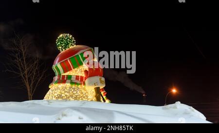 Luci da neve colorate e brillanti con berretto a righe e sciarpa, bottoni neri e naso di carota hanno fatto salire una mano accogliente nei guanti. Foto Stock