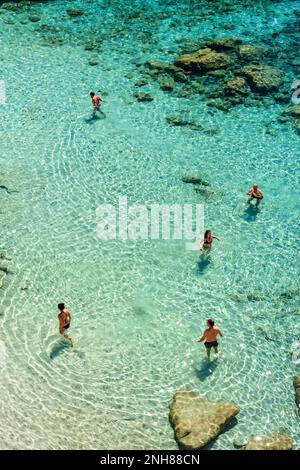 Turisti che nuotano nelle limpide acque della spiaggia di Tsigrado, Milos Foto Stock