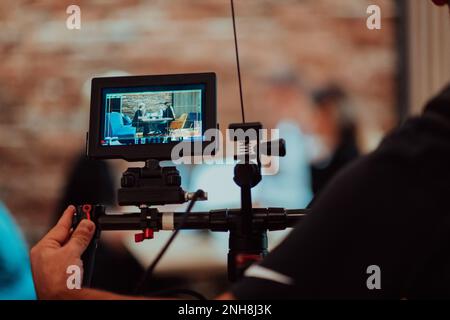 Behinde le scene. Un cameraman registra una riunione di lavoro che viene trasmessa in streaming sui canali televisivi Foto Stock