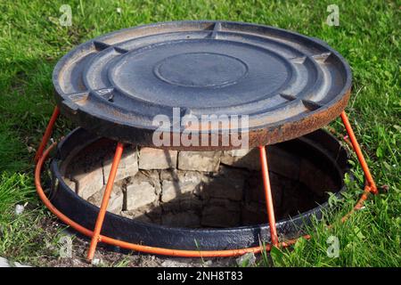 Aprire bene portello sul prato verde. Il coperchio del pozzetto d'ispezione è sul supporto. Dispositivo per la ventilazione di pozzi.. Foto Stock