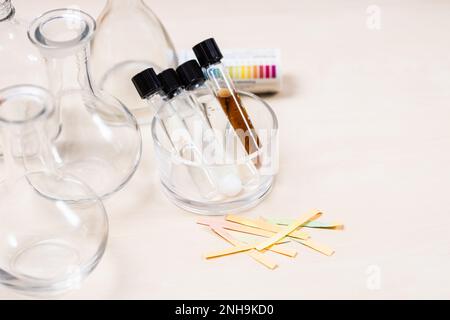 provette con liquidi e soluzioni, matracci e carte indicatrici su un tavolo luminoso con spazio di copyspace Foto Stock