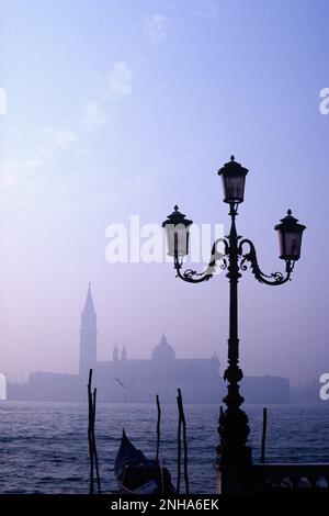 Italia. Venezia. Misty lungomare con lampione e gondola. Foto Stock