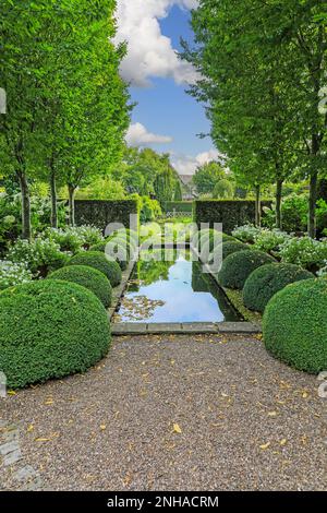 Lo stagno ed il topiary al giardino superiore del Rill a Wollerton vecchio giardino della Hall, Wollerton, Drayton del mercato, Shropshire, Inghilterra, REGNO UNITO Foto Stock