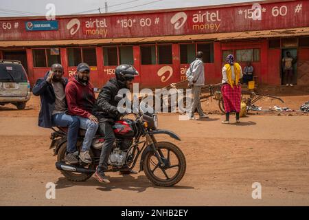 Karatu, Tanzania - 16th ottobre 2022: Un pilota di cabina motociclista con due passeggeri su una strada di Karatu, Tanzania, in una giornata di sole. Foto Stock